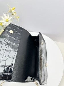 Macro detail of black crocodile pattern bag with gold magnetic snap button closure