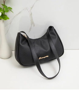 Detail of black lychee grain leather underarm bag with gold logo and marble background