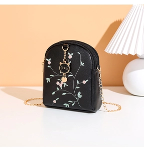 Détail de broderie florale sur petit sac à bandoulière noir avec chaîne dorée élégante