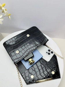 Detail view of black crocodile pattern chain bag showing interior storage and gold hardware