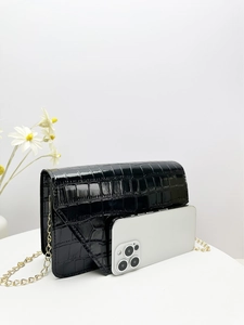 Detailed size comparison of black croc-effect chain bag next to a smartphone