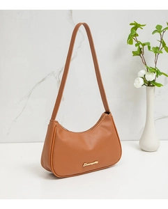 Detail of a brown lychee-patterned hobo bag with a gold metal Seventy logo on a white desk