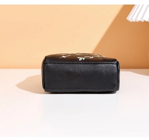 Détail de la broderie florale sur le sac en cuir grainé noir avec des coutures soignées