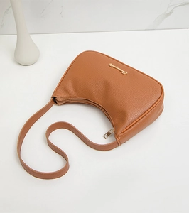 Close-up of brown litchi pattern leather crescent bag with gold metal logo detail
