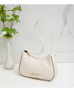 Detail of cream-colored lychee textured leather underarm bag with gold logo and brown piping