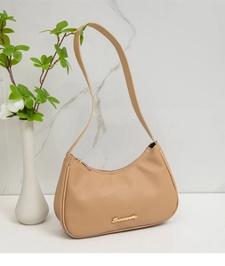 Detail of tan lychee grain leather hobo bag with gold logo on white marble background