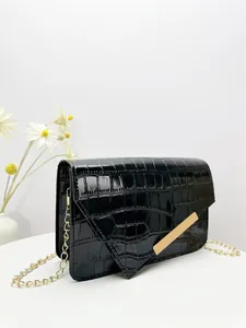 Detail of black faux crocodile skin envelope bag with delicate gold chain strap