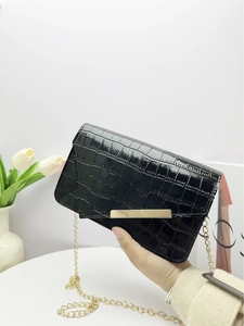 Close-up of black crocodile pattern envelope bag with gold metal bar and chain strap