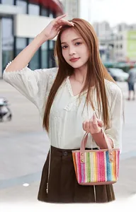 Detail of colorful rainbow straw tote bag with pink leather handles and gold stud accents