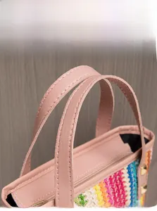 Detail of pink faux leather handle and rainbow straw woven texture with gold rivets