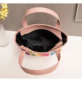 Top view of rainbow straw tote with pink leather handles and black fabric lining detail