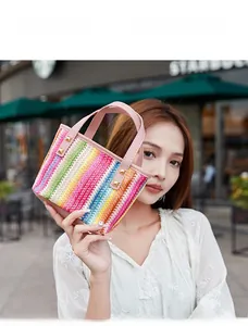 Detail of colorful woven mini tote bag featuring pink leather handles and gold rivets