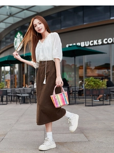 Chic girl holding colorful woven mini tote bag with pink leather handle and rivets detail