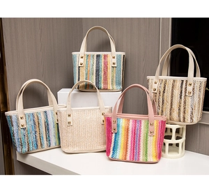 Various colors of woven straw tote bags with golden studs shown on display stands