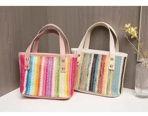 Detail of colorful striped woven straw handbags with chic leather handles and gold studs