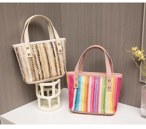 Detailed close-up of straw woven tote bags featuring colorful stripes and gold stud accents