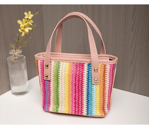 Detail of colorful woven tote bag featuring pink leather handles and gold square rivets