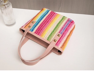 Detail of rainbow striped woven tote bag with pink faux leather handle and gold studs
