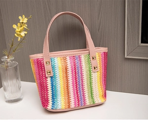 Detail of colorful woven tote bag featuring rainbow stripes and pink leather handles
