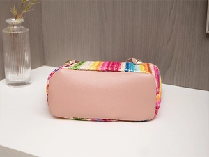 Detailed bottom view of colorful woven tote featuring pink faux leather and gold studs