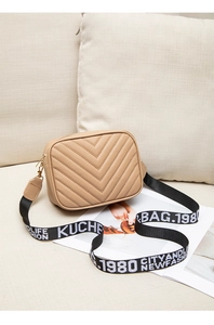 Detail der beigen Stepptasche mit V-Muster und gemustertem breitem Schultergurt-Design