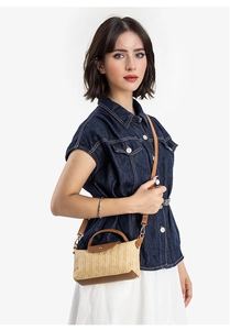 Detail of straw mini square bag with brown leather flap and detachable shoulder strap