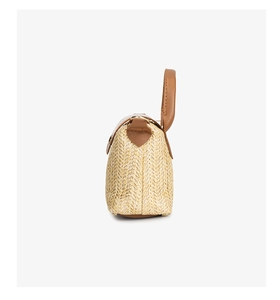 Detailed side view of woven straw bag with premium leather handle and metal D-rings