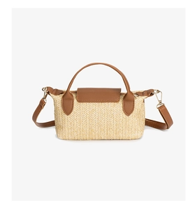 Detailed view of woven straw texture with brown leather flap and golden metal hardware