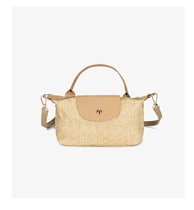Detailed view of the woven straw texture and leather flap on a beige crossbody bag