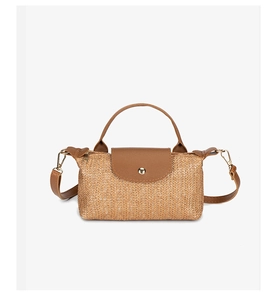 Detail of woven straw texture and dark brown leather flap on a summer crossbody bag