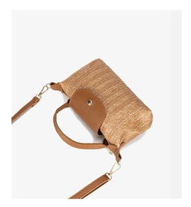 Close-up of woven straw texture with brown leather flap and golden magnetic clasp
