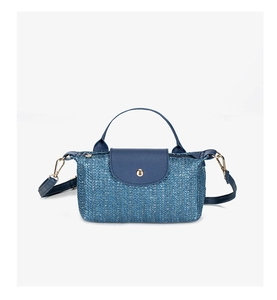 Close-up of blue woven straw texture with navy leather trim and golden metal snap button