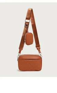 Detail of orange-brown quilted camera bag with wide strap and mini round coin purse