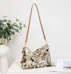 Détail de la texture des paillettes dorées sur un sac à bandoulière chic avec lanière cuir