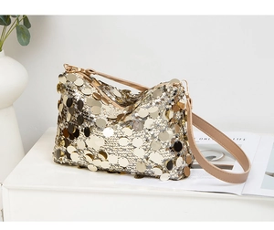 Détail d'un sac porté épaule élégant avec paillettes or et argent sur table blanche