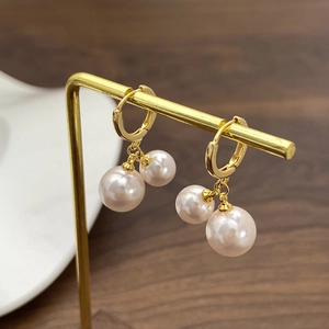 Macro shot of double shell pearl drop earrings on a golden stand with elegant jewelry details