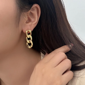 Golden link chain earrings with three interlocking oval hoops on a female model