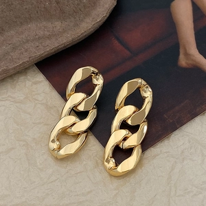 Detailed view of chunky triple-link gold chain earrings on a stylish vintage background
