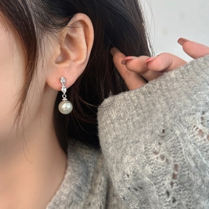 Vue macro de boucles d'oreilles perles grises avec oxydes de zirconium sur l'oreille