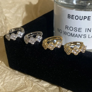 Luxury clover hoop earrings with zircon stones in silver and gold displayed on velvet