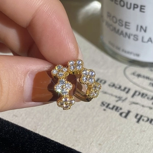 Close-up of gold-plated hoop earrings featuring zircon four-leaf clover clusters