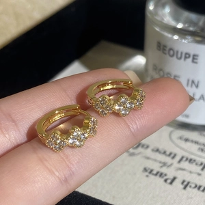 Detailed shot of gold plated hoop earrings with three zircon-encrusted clovers