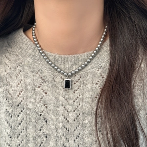 Elegant pearl necklace with rectangular black pendant and zircon inlay on gray sweater