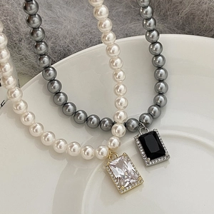 Luxe pearl necklaces with zircon pendants in gold and silver finish on ceramic tray