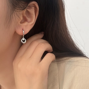 Detailed view of silver hoop earrings featuring a hollow butterfly pendant on a model
