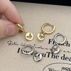Gold and silver plated hollow butterfly charm hoop earrings shown on textured fabric