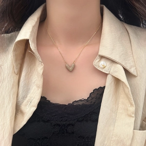 Dettaglio della collana a catena dorata con ciondolo a cuore tortora su modella