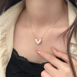 Dettaglio della collana d'oro con pendente a cuore in marmo rosa indossata da una modella