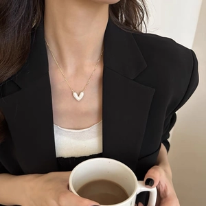 Dettaglio di un'elegante collana a cuore con catena d'oro e ciondolo in perla crema