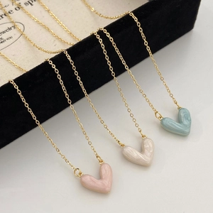 Dettaglio di ciondoli a cuore in rosa, bianco e blu con trama marmorea su catene d'oro